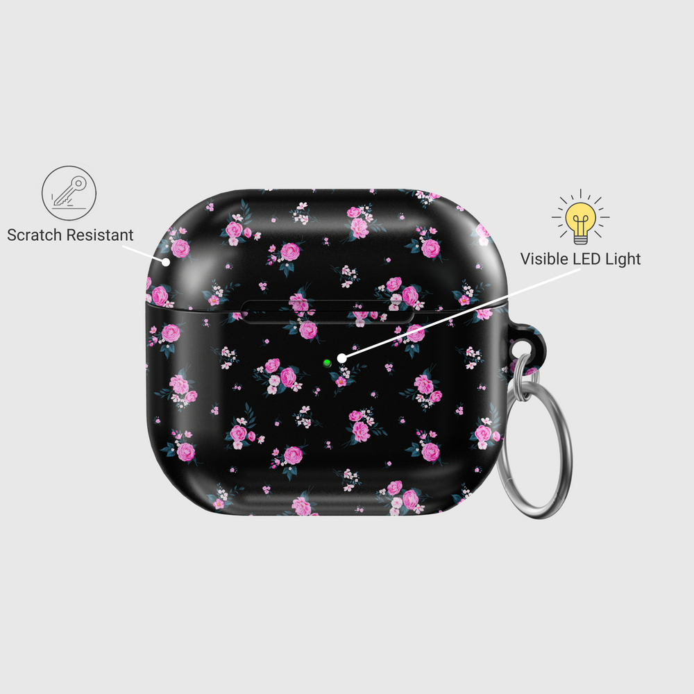 Glossy black AirPods case featuring scattered pink rose floral pattern with mini white accents, paired with a silver keychain—stylish and protective for music lovers on the go.
