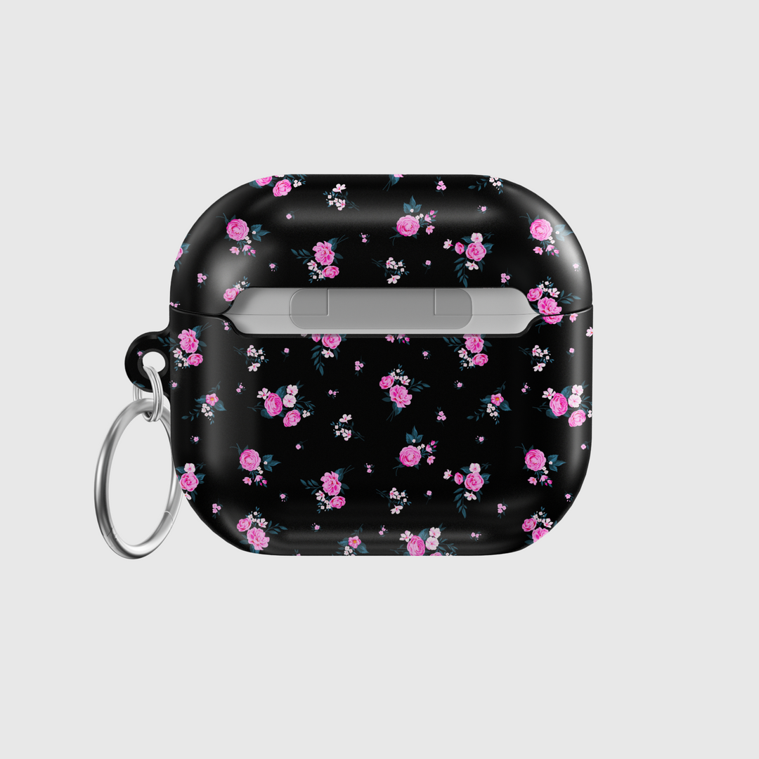 Glossy black AirPods case featuring scattered pink rose floral pattern with mini white accents, paired with a silver keychain—stylish and protective for music lovers on the go.