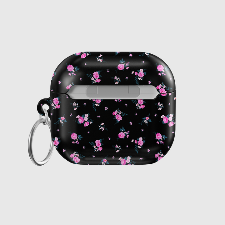 Glossy black AirPods case featuring scattered pink rose floral pattern with mini white accents, paired with a silver keychain—stylish and protective for music lovers on the go.