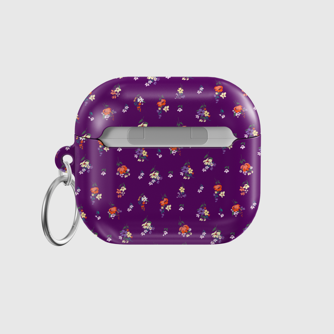 Glossy purple AirPods case with delicate mini floral bouquet pattern in red, orange, yellow, and white, complete with a silver keychain—perfect for a music lover with a soft spot for bold floral style.