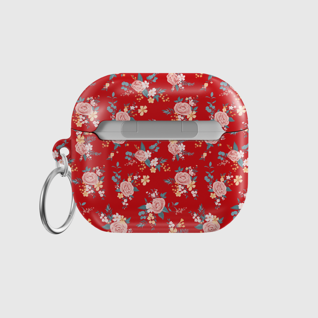 Glossy red AirPods case featuring delicate vintage-style floral print with soft pink roses and blue leaves, paired with a silver keychain—ideal for romantic, music-loving aesthetics.