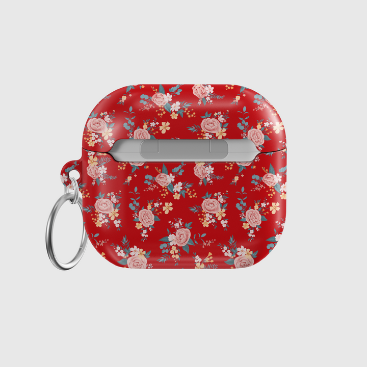 Glossy red AirPods case featuring delicate vintage-style floral print with soft pink roses and blue leaves, paired with a silver keychain—ideal for romantic, music-loving aesthetics.