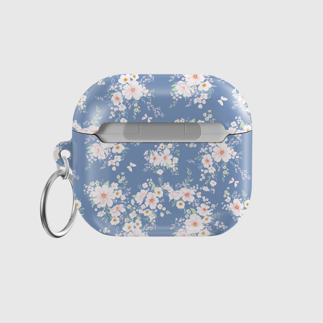 AirPods case with a soft blue background and delicate white and blush floral pattern, featuring a glossy finish and silver keychain, designed for music lovers who adore a romantic and vintage aesthetic.