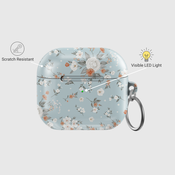 Stylish blue AirPods case with delicate peach and white floral print, featuring a glossy finish and silver keychain ring. A soft, music-inspired accessory for AirPods Pro and AirPods 3.