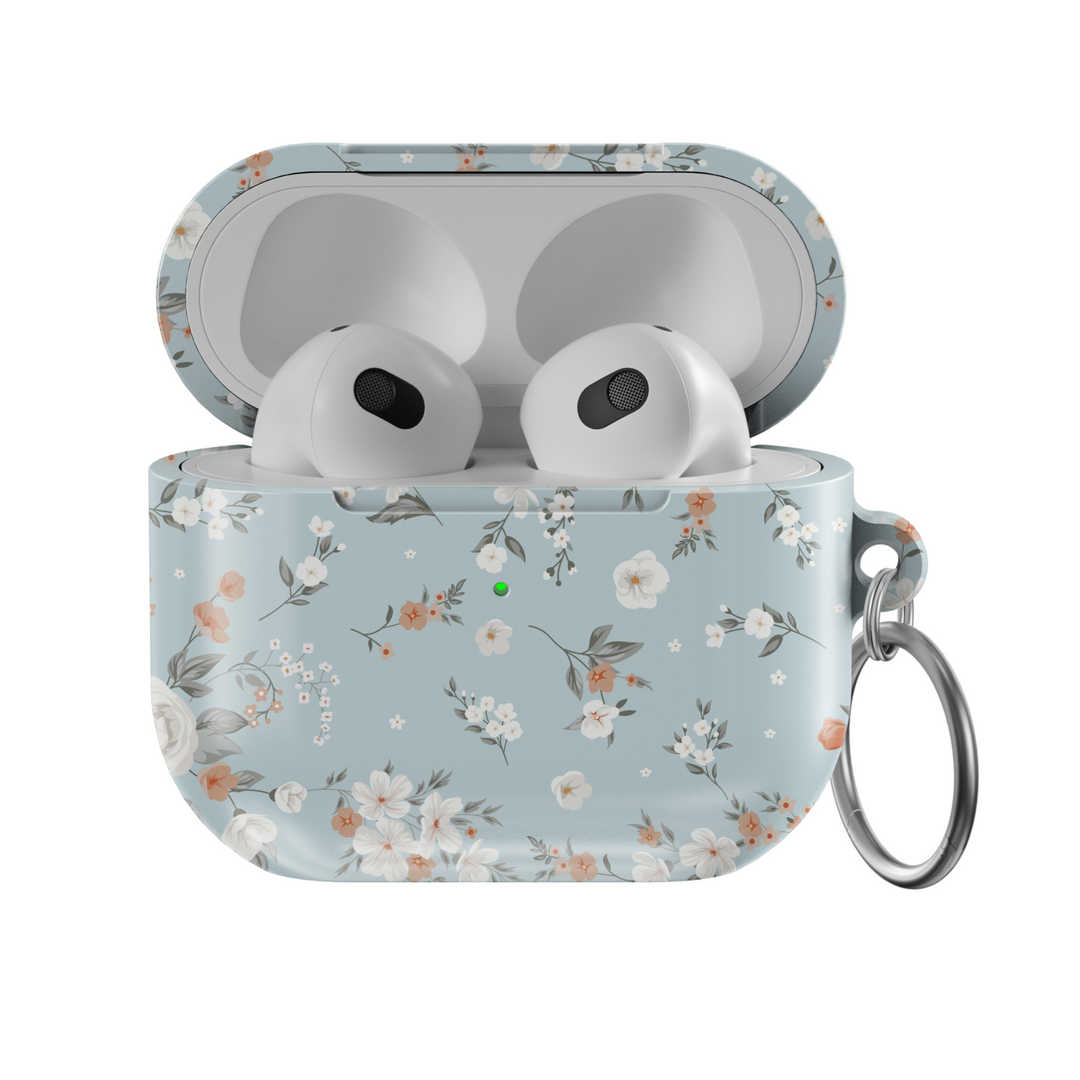 Stylish blue AirPods case with delicate peach and white floral print, featuring a glossy finish and silver keychain ring. A soft, music-inspired accessory for AirPods Pro and AirPods 3.