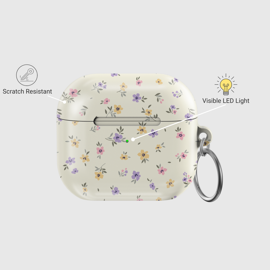 AirPods case with a cream background and tiny pastel floral print in lavender, yellow, and pink, finished with a glossy texture and keychain loop.