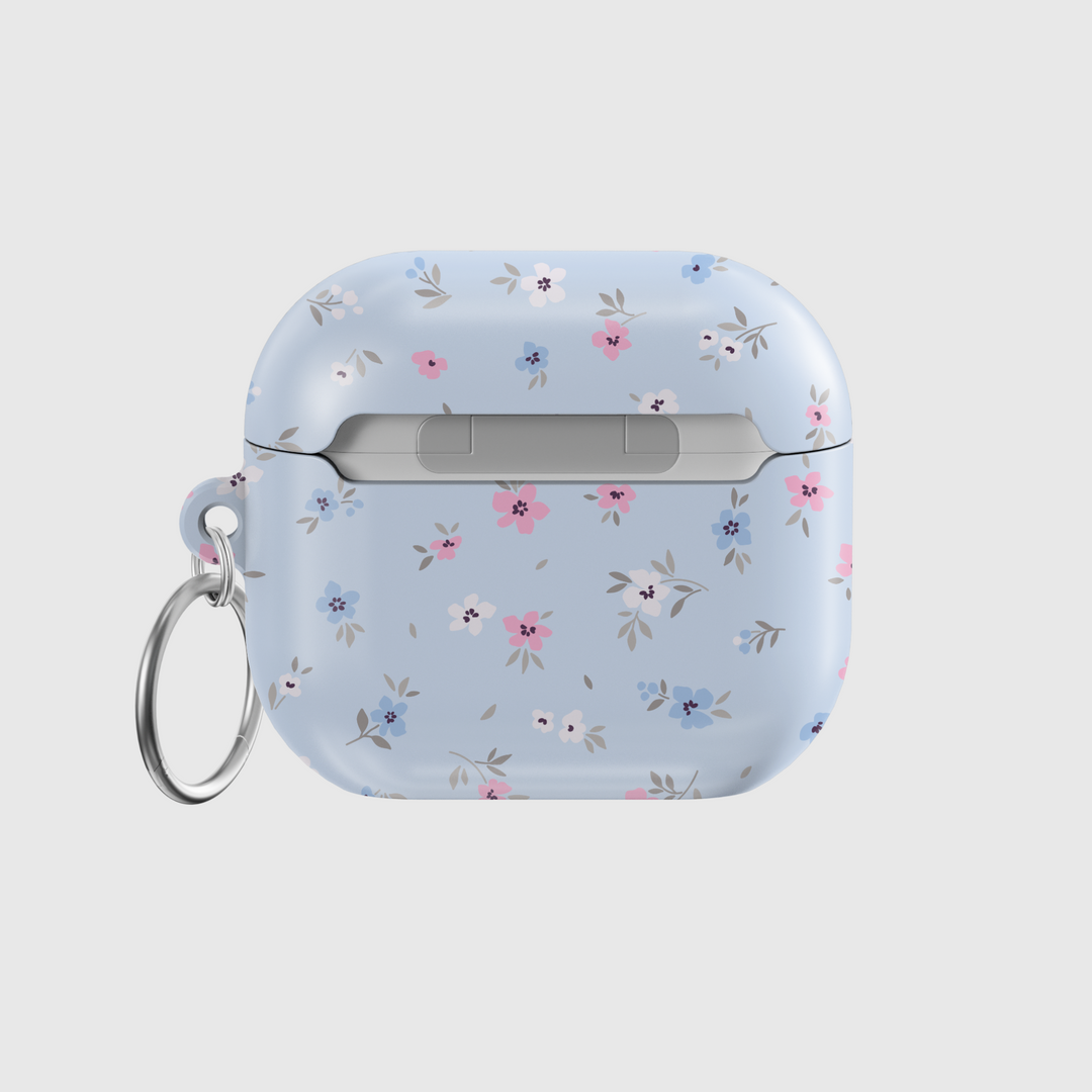 Glossy baby blue AirPods case with delicate pink, white, and blue floral print and silver keychain—pastel aesthetic and soft feminine design