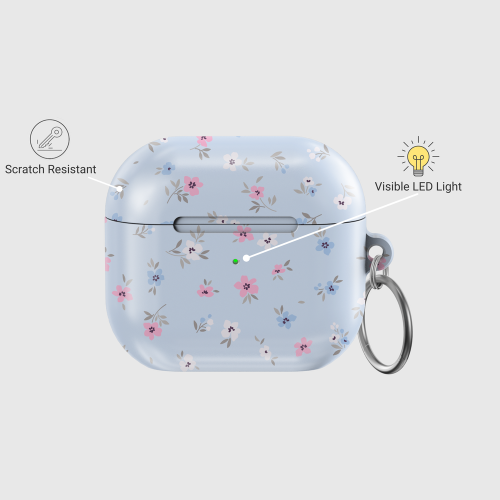 Glossy baby blue AirPods case with delicate pink, white, and blue floral print and silver keychain—pastel aesthetic and soft feminine design