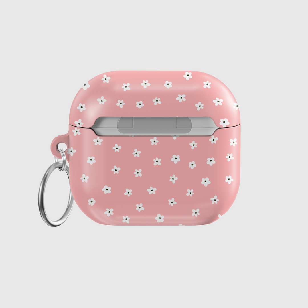 Soft pink AirPods case featuring a pattern of tiny white flowers with a glossy finish and silver keychain, perfect for a girly, floral aesthetic.