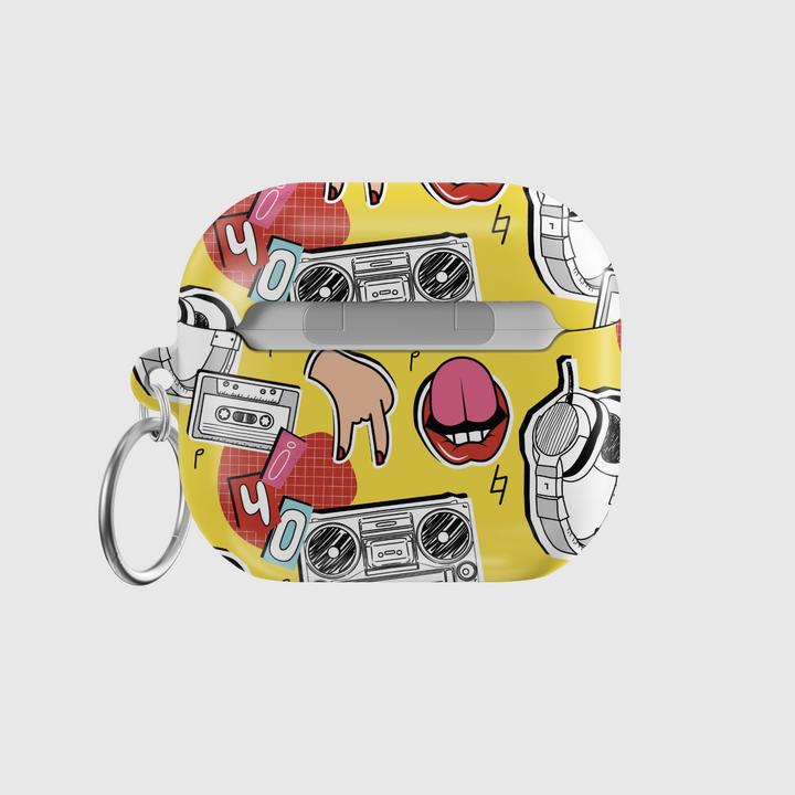 Yellow AirPods case with pop art design featuring boombox, cassette tape, tongue-out lips, headphones, and retro icons in bold cartoon style with a glossy finish and keychain.