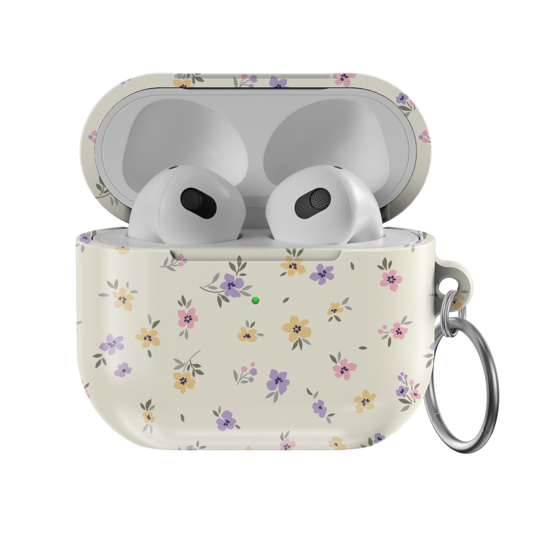 AirPods case with a cream background and tiny pastel floral print in lavender, yellow, and pink, finished with a glossy texture and keychain loop.