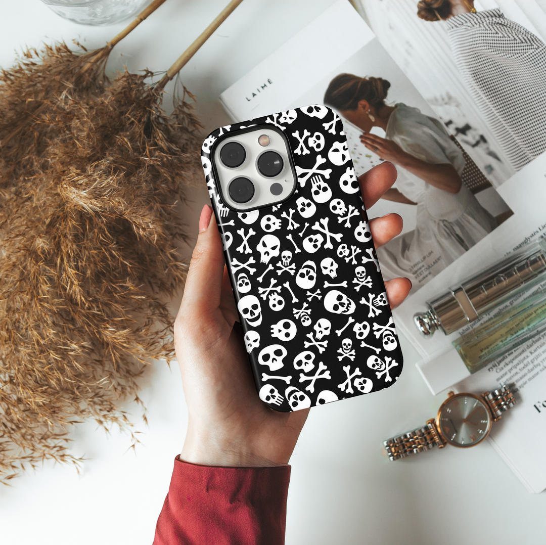 Black iPhone case with white skull and crossbones pattern, Halloween skeleton aesthetic, spooky gothic phone cover, scary skull print for iPhone 16, 15, 14, 13.