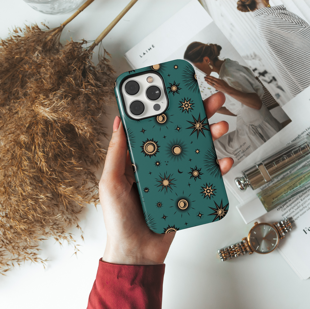 Teal iPhone case with mystical celestial pattern featuring gold-toned suns, moons, and stars in a vintage-style cosmic design.