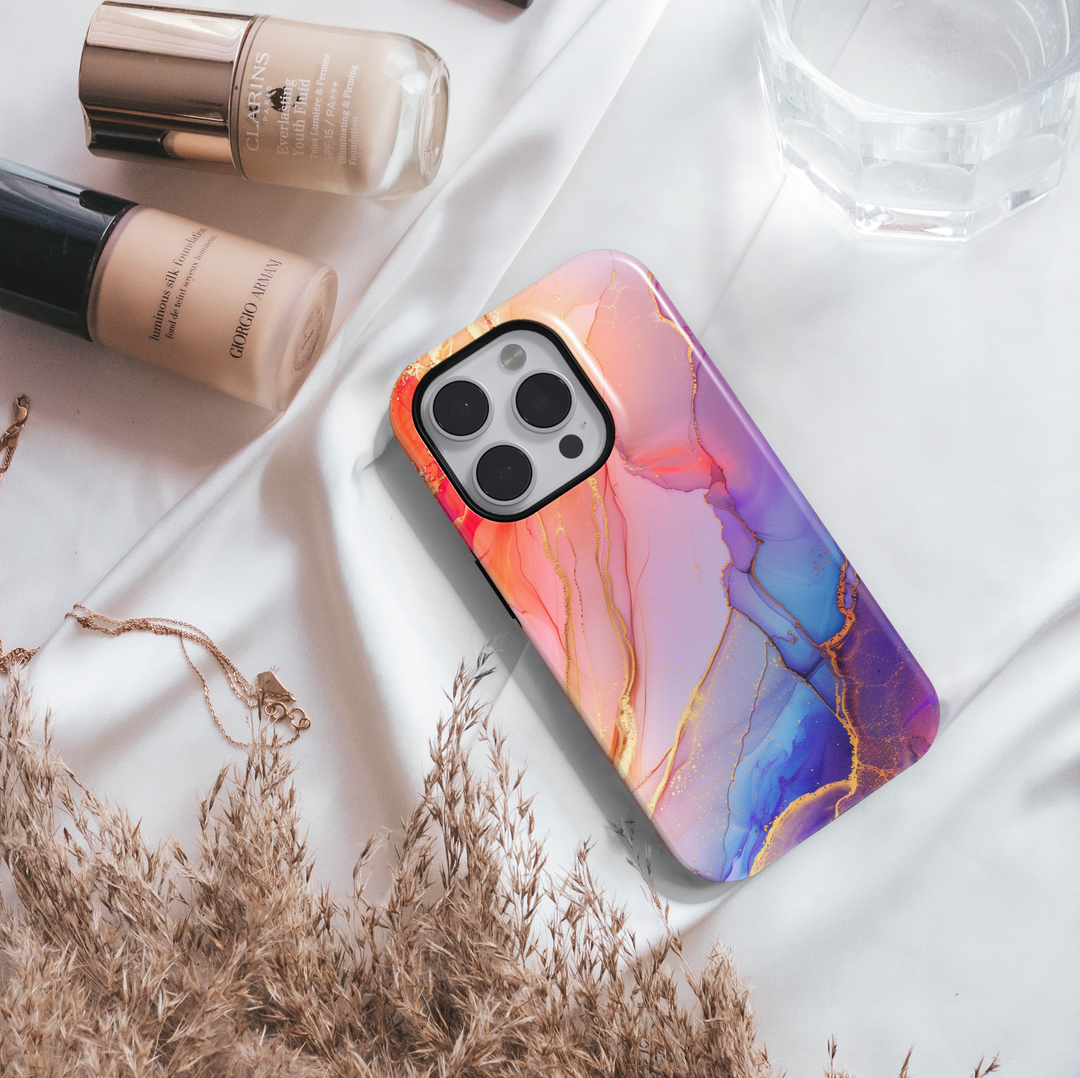 Elegant blush pink and violet marble swirl iPhone 16 MagSafe case with gold accents and fluid abstract design.