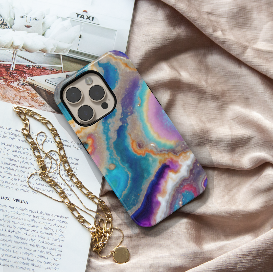 Tough iPhone 16 MagSafe case featuring a colorful geode swirl pattern in turquoise, purple, gold, and white with a glossy finish.