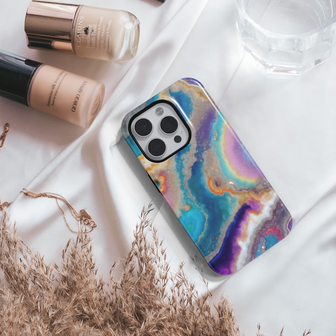 Tough iPhone 16 MagSafe case featuring a colorful geode swirl pattern in turquoise, purple, gold, and white with a glossy finish.