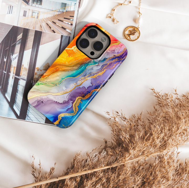 Colorful rainbow marble swirl iPhone 16 MagSafe case with fluid abstract art in yellow, orange, blue, green, and purple hues with gold accents.