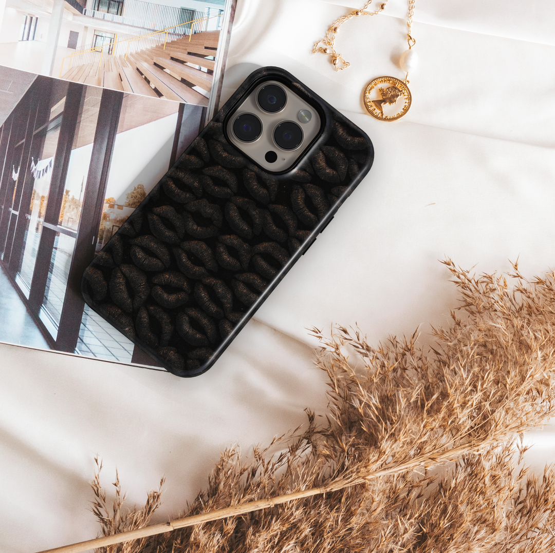 Glossy black iPhone case featuring a textured dark lip print pattern, stylish and edgy design for iPhone 16 series, MagSafe compatible.