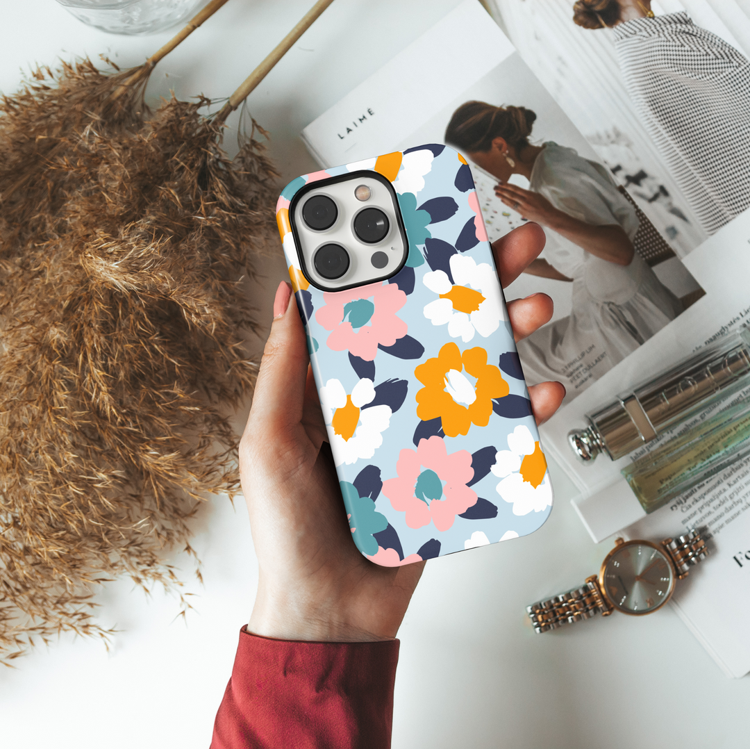 Cute iPhone case with abstract floral print in pastel pink, teal, white, and mustard yellow on a light blue background. Perfect for spring or summer aesthetics.