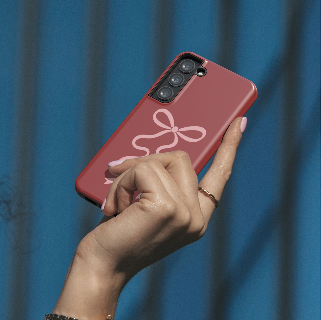 Deep red Samsung Galaxy phone case with soft pink ribbon bow – compatible with Galaxy S24 Ultra, S25, S24 FE. Elegant coquette aesthetic case for women.