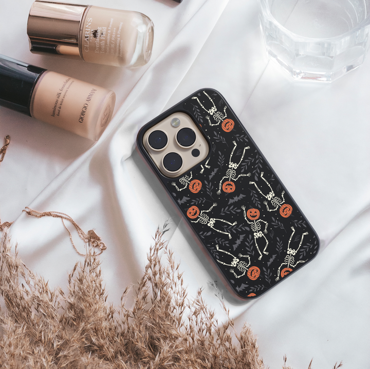 Pumpkin Skeleton iPhone Case, Halloween iPhone cover with spooky skeletons and pumpkin heads, cute gothic phone case with black background, protective fall phone case, stylish skeleton iPhone cover