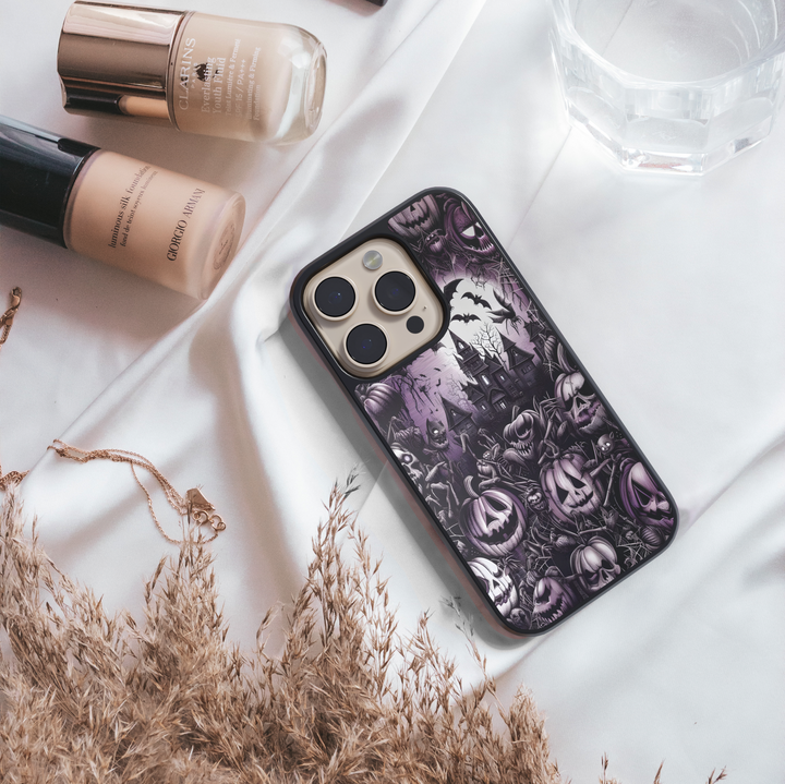 Halloween iPhone case with haunted mansion design, purple gothic background, creepy jack-o’-lantern pumpkins, bats, cobwebs, skulls, and eerie spooky graveyard pattern – protective shockproof phone cover for iPhone