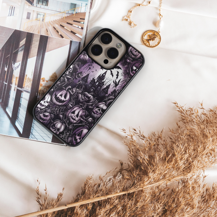Halloween iPhone case with haunted mansion design, purple gothic background, creepy jack-o’-lantern pumpkins, bats, cobwebs, skulls, and eerie spooky graveyard pattern – protective shockproof phone cover for iPhone