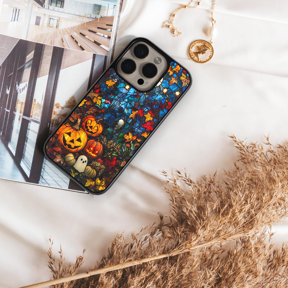 Halloween iPhone case with stained-glass style design, featuring glowing jack-o’-lantern pumpkins, ghost illustration, and colorful autumn leaves, protective fall aesthetic phone cover
