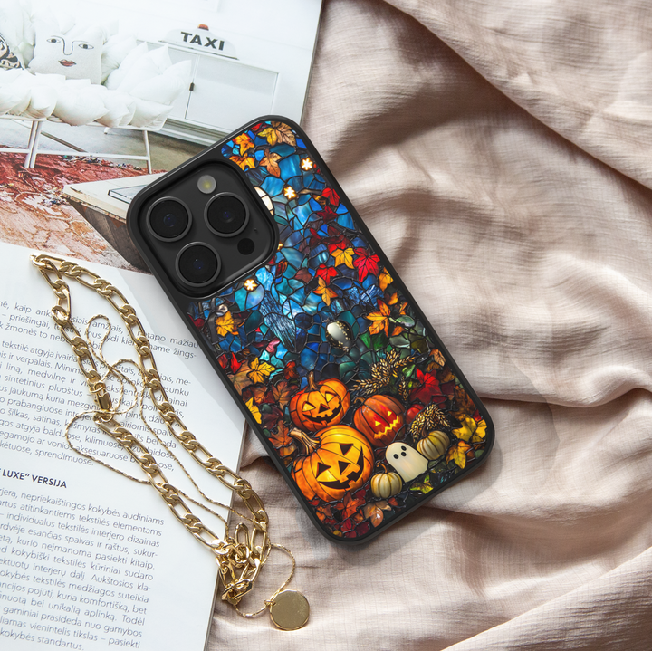 Halloween iPhone case with stained-glass style design, featuring glowing jack-o’-lantern pumpkins, ghost illustration, and colorful autumn leaves, protective fall aesthetic phone cover