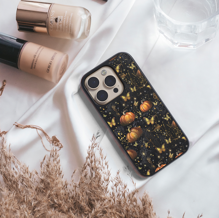 Halloween phone case with glowing golden butterflies, orange pumpkins, and sparkling details on a black background, aesthetic fall iPhone cover