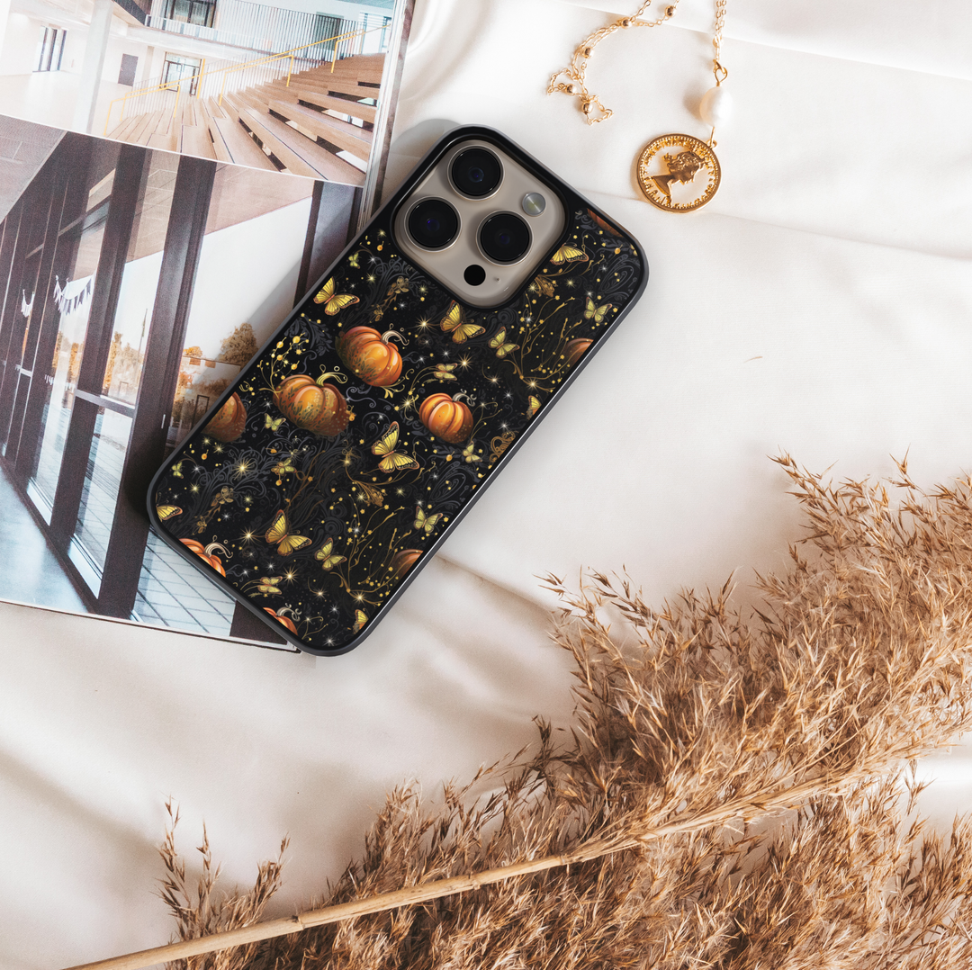 Halloween phone case with glowing golden butterflies, orange pumpkins, and sparkling details on a black background, aesthetic fall iPhone cover