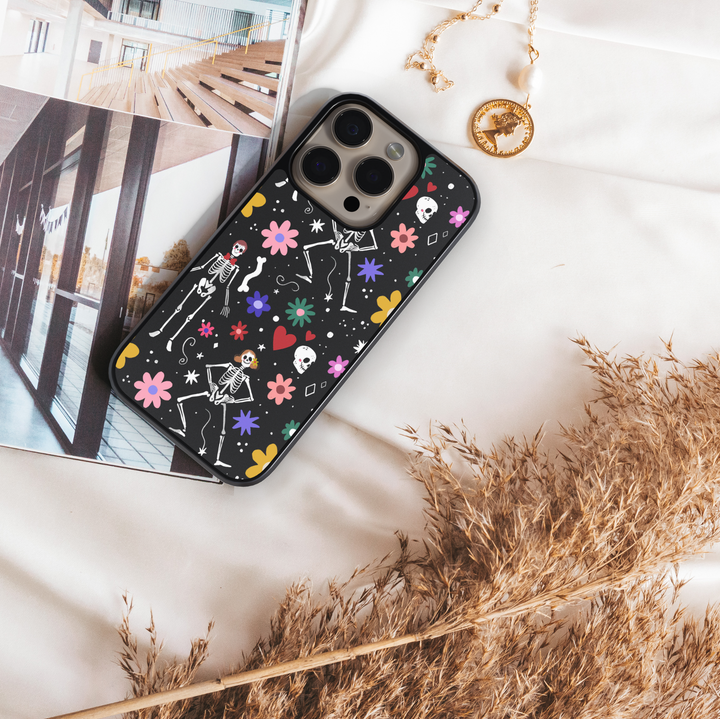 Black iPhone case with colorful skeletons, flowers, and hearts – cute Halloween girly aesthetic phone cover