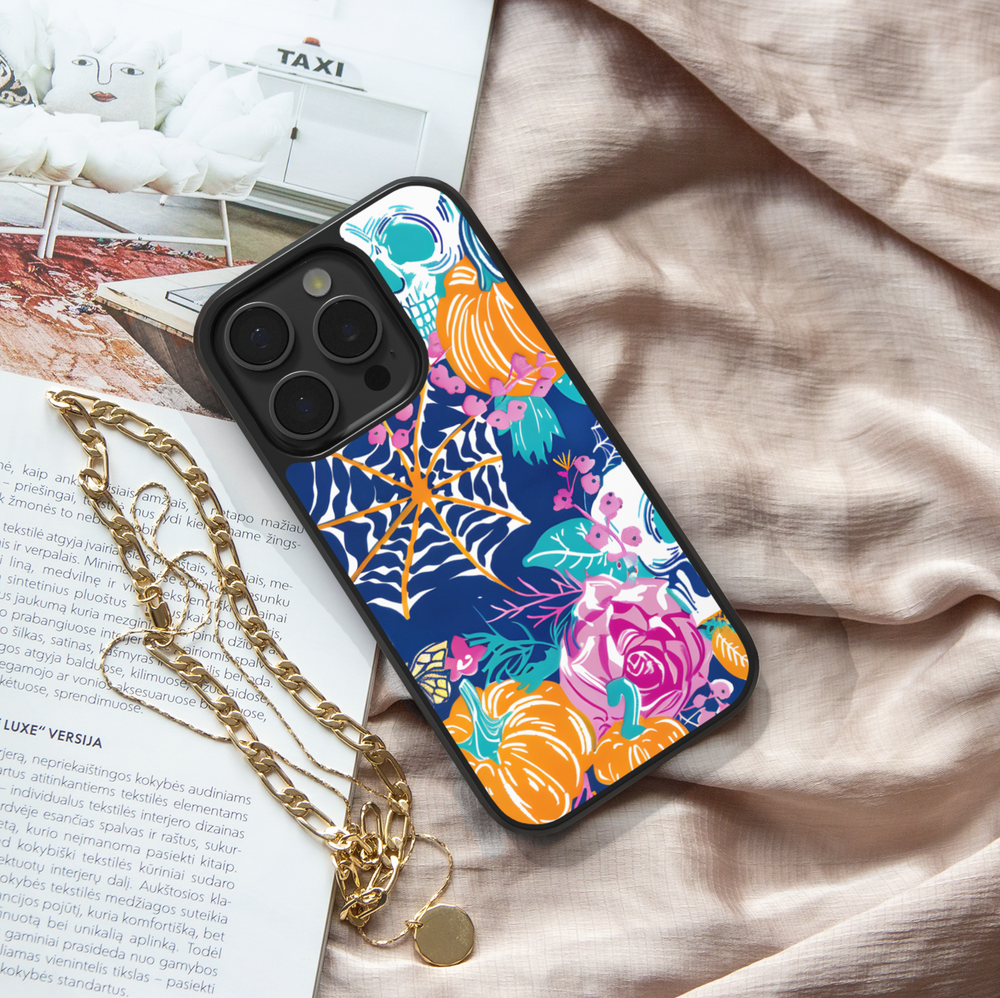 Midnight Bloom iPhone case with pumpkins, skull, spider web, and colorful floral design on navy background.