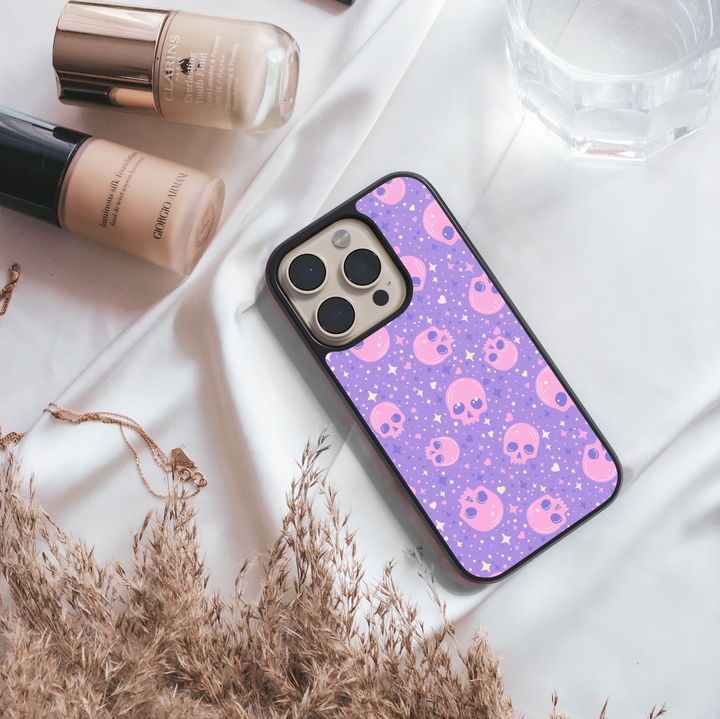 Pastel skull iPhone case with purple background, sparkly stars, pink kawaii skull pattern, gothic cute phone cover, aesthetic Halloween iPhone accessory