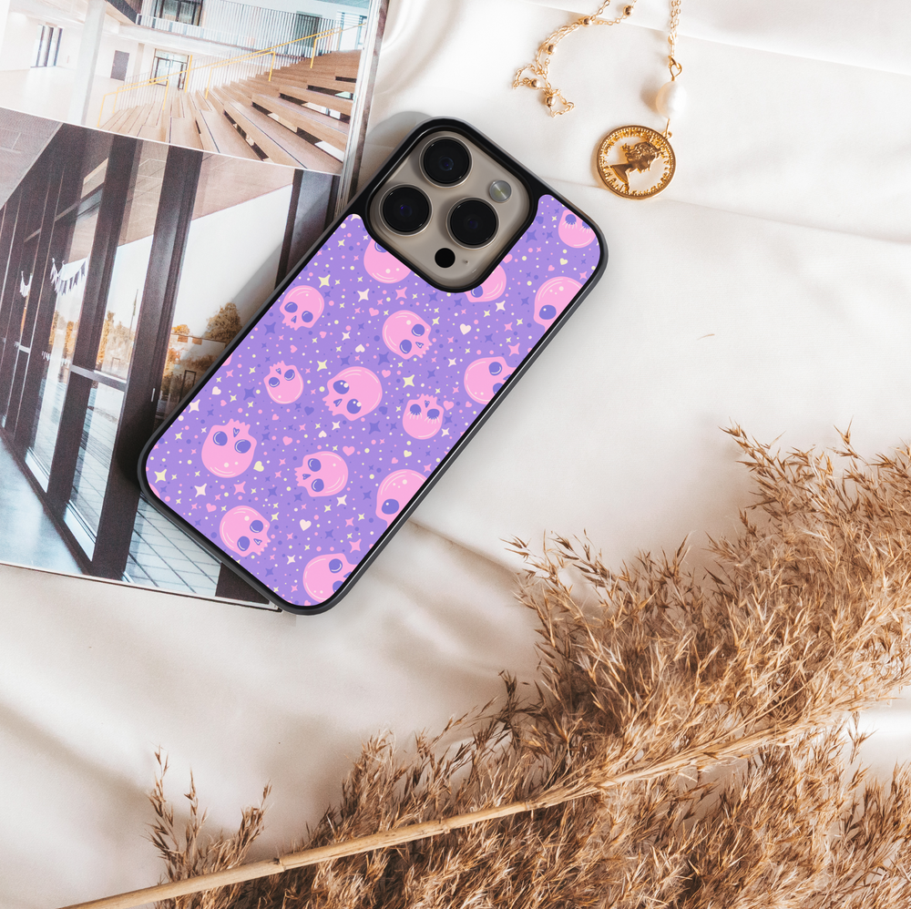 Pastel skull iPhone case with purple background, sparkly stars, pink kawaii skull pattern, gothic cute phone cover, aesthetic Halloween iPhone accessory