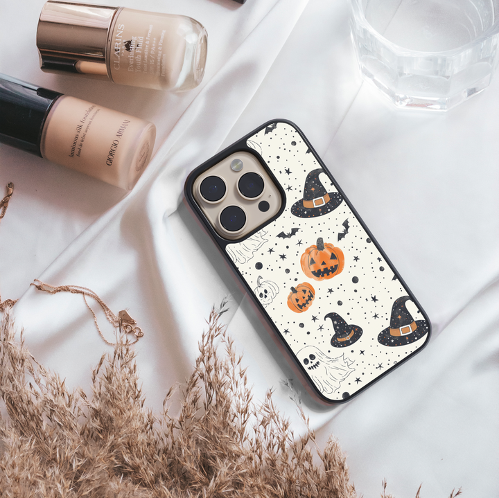 Halloween pumpkin and witch hat iPhone case with ghost, bat, and star pattern on cream background.