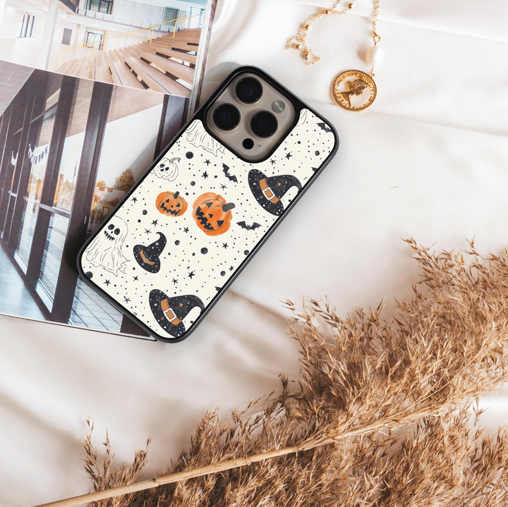 Halloween pumpkin and witch hat iPhone case with ghost, bat, and star pattern on cream background.