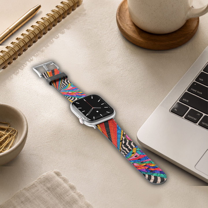 Lifestyle image of a colorful stained glass Apple Watch band featuring vibrant abstract mosaic artwork with rainbow colors, zebra accents, and premium vegan leather, shown in feminine desk setting. Compatible with Apple Watch Series 1–10, SE, Ultra, and Ultra 2.