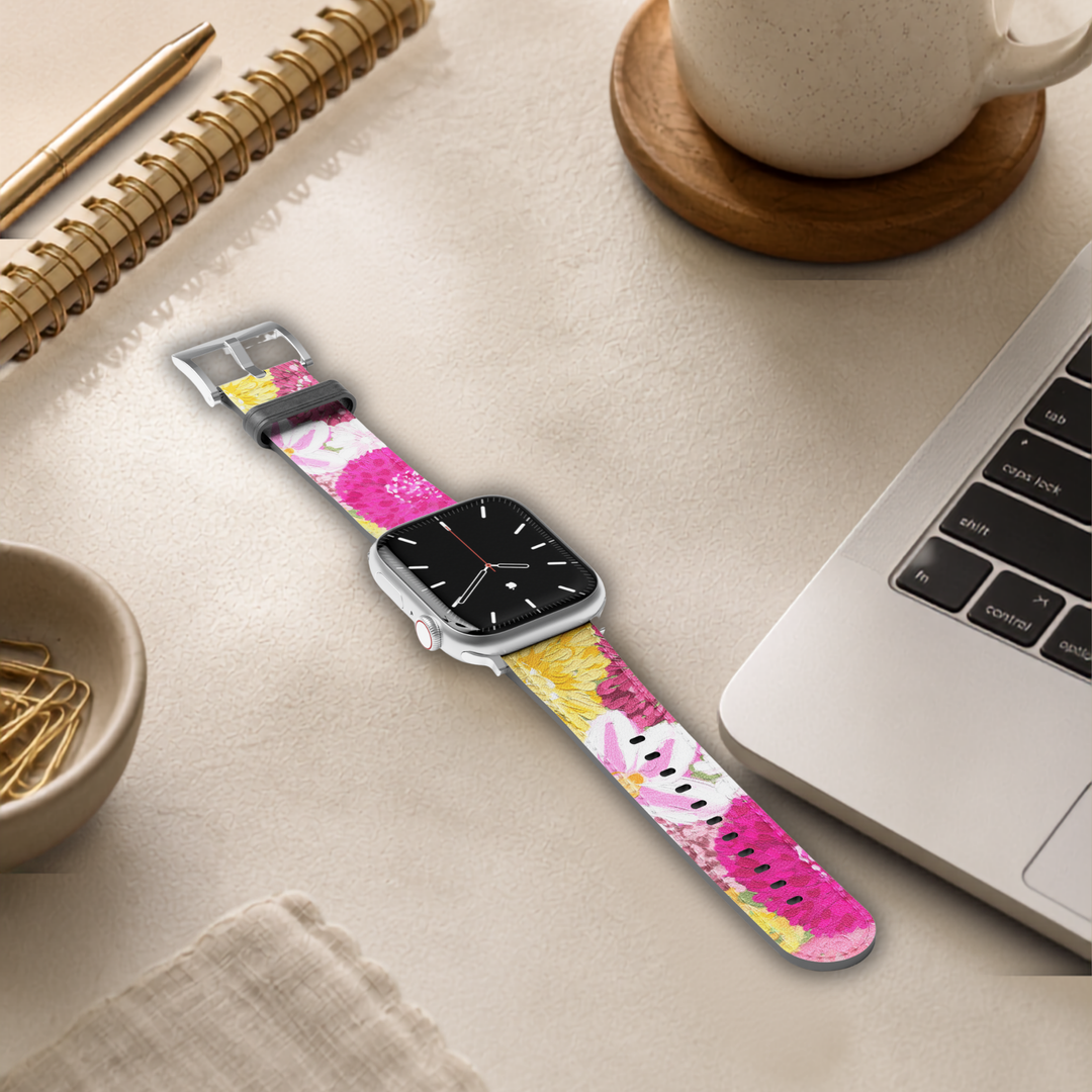 Bloom Belle floral Apple Watch band featuring vibrant pink, yellow, and white flowers printed on premium vegan leather with a soft faux-suede interior and stainless steel buckle. Compatible with Apple Watch Series 1–10, SE, Ultra, and Ultra 2.