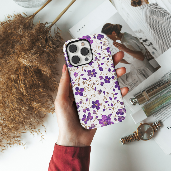 Purple floral iPhone case with shimmering gold accents and delicate vines on a light silver background. Elegant, girly, and perfect for a chic everyday look.