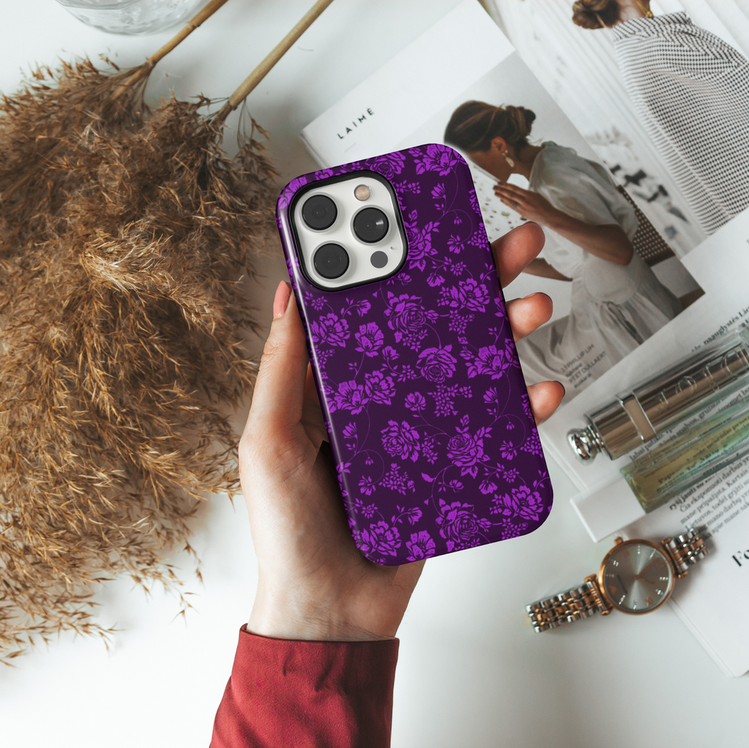 Elegant purple floral iPhone case with intricate rose and vine pattern on a deep violet background, perfect for a moody fall or Halloween aesthetic.