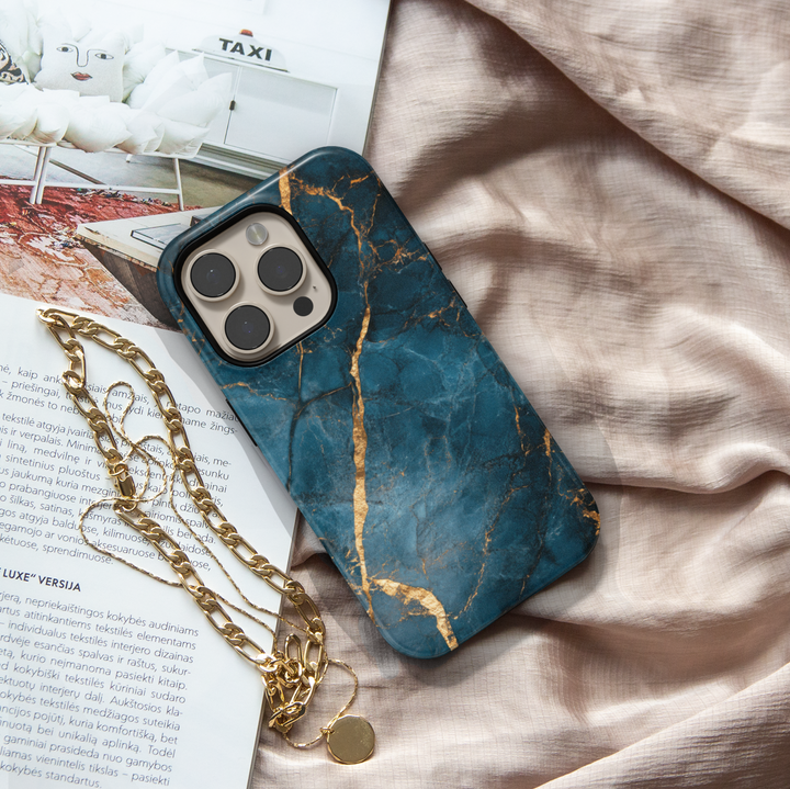 Elegant iPhone case with deep blue marble texture and gold vein detailing; MagSafe-compatible tough case for iPhone 16.
