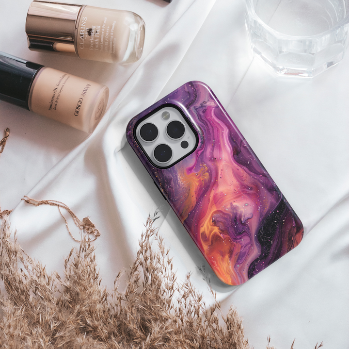 Vibrant iPhone case with a swirling abstract galaxy design in purples, oranges, and black; bold MagSafe-compatible tough case for iPhone 16.

