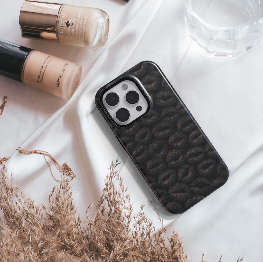 Glossy black iPhone case featuring a textured dark lip print pattern, stylish and edgy design for iPhone 16 series, MagSafe compatible.