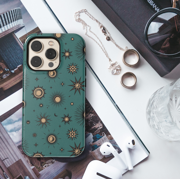 Teal iPhone case with mystical celestial pattern featuring gold-toned suns, moons, and stars in a vintage-style cosmic design.