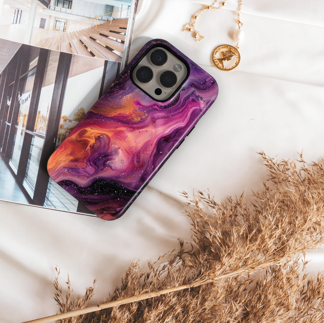 Vibrant iPhone case with a swirling abstract galaxy design in purples, oranges, and black; bold MagSafe-compatible tough case for iPhone 16.

