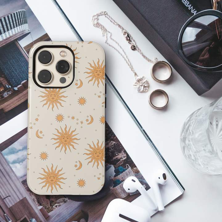 Cream celestial iPhone case with vintage orange sun faces, crescent moons, and scattered stars in a hand-drawn style.