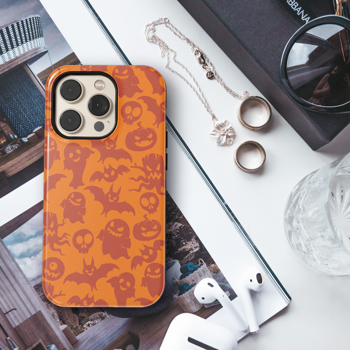 Orange Halloween iPhone case featuring a seamless pattern of spooky red ghosts, bats, pumpkins, skulls, and creepy eyes for a fun and festive look.