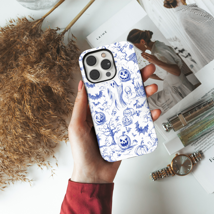 Halloween phone case with blue sketch illustrations of ghosts, bats, jack-o'-lanterns, haunted trees, skulls, and a spooky castle on a white background.