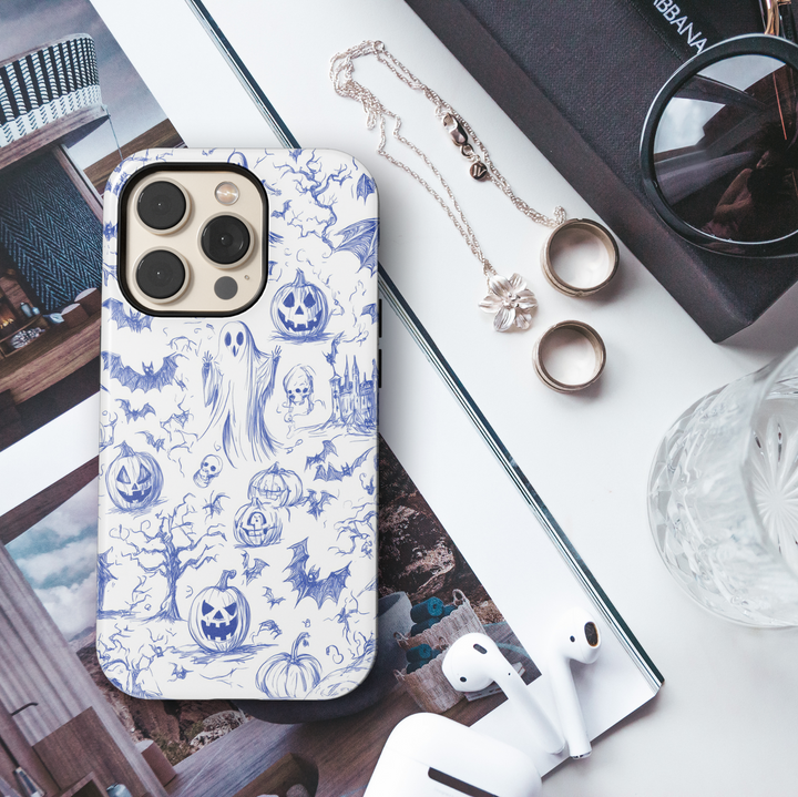 Halloween phone case with blue sketch illustrations of ghosts, bats, jack-o'-lanterns, haunted trees, skulls, and a spooky castle on a white background.